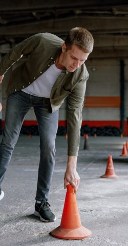 Motorbike driving school lesson with instructor putting cone on track front of student. Indoor motodrome training center